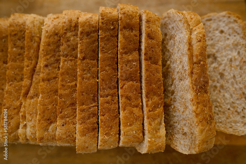 close-up toast appetizing fresh wholemeal bread with bran sliced in layers on wooden board, wheat, multigrain bread topview, bakery pastries, gluten products, diet, wholesome food, healthy eating