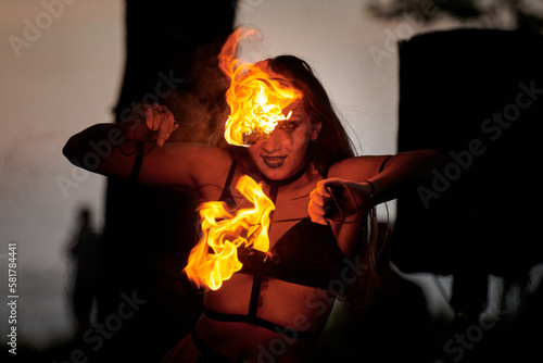 Obraz na plátně Girl fire dancing performance at outdoor art festival, smooth movements of female fire show artist with torch