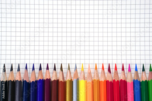 Colored pencils or pastel lined up placed on graph book. Learning, study and presentation concept.