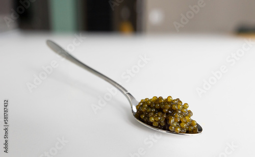 Photography a levitating teaspoon with black sturgeon caviar on the table