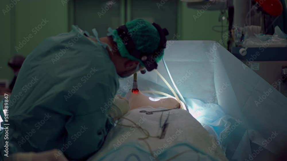 Expert surgeon widens hole in bust of unrecognizable woman for breast implant. Medium shot of concentrated professional Middle Eastern doctor performing augmentation surgery in slow motion Expert surgeon widens hole in bust of unrecognizable woman for breast implant. Medium shot of concentrated professional Middle Eastern doctor performing augmentation surgery in slow motion