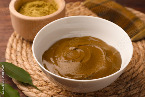 Bowl of henna cream on wooden table  closeup. Natural hair coloring