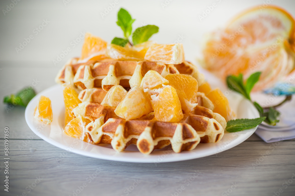 Cooked sweet Belgian waffles with oranges on the table. Cooked sweet Belgian waffles with oranges on the table.