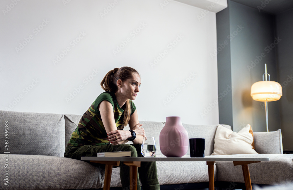 Portrait of depressed female soldier at home sitting on sofa. Portrait of depressed female soldier at home sitting on sofa.