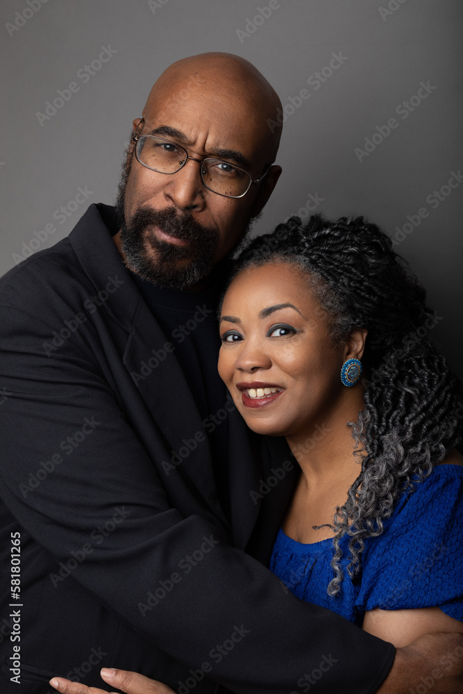 Studio portrait of an attractive middle aged black married couple. They are embracing and smiling. 