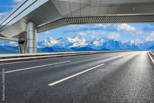 Asphalt road and pedestrian bridge with snow mountain background