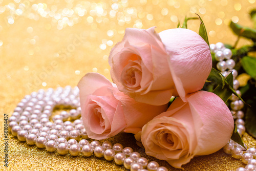 Fototapeta Naklejka Na Ścianę i Meble -  Pink rose and pearl necklace on a shiny gold background
