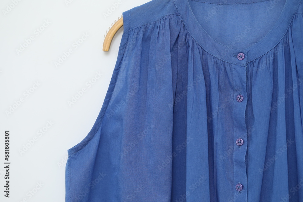 Blue colour blouse is clothes hanger on white background.