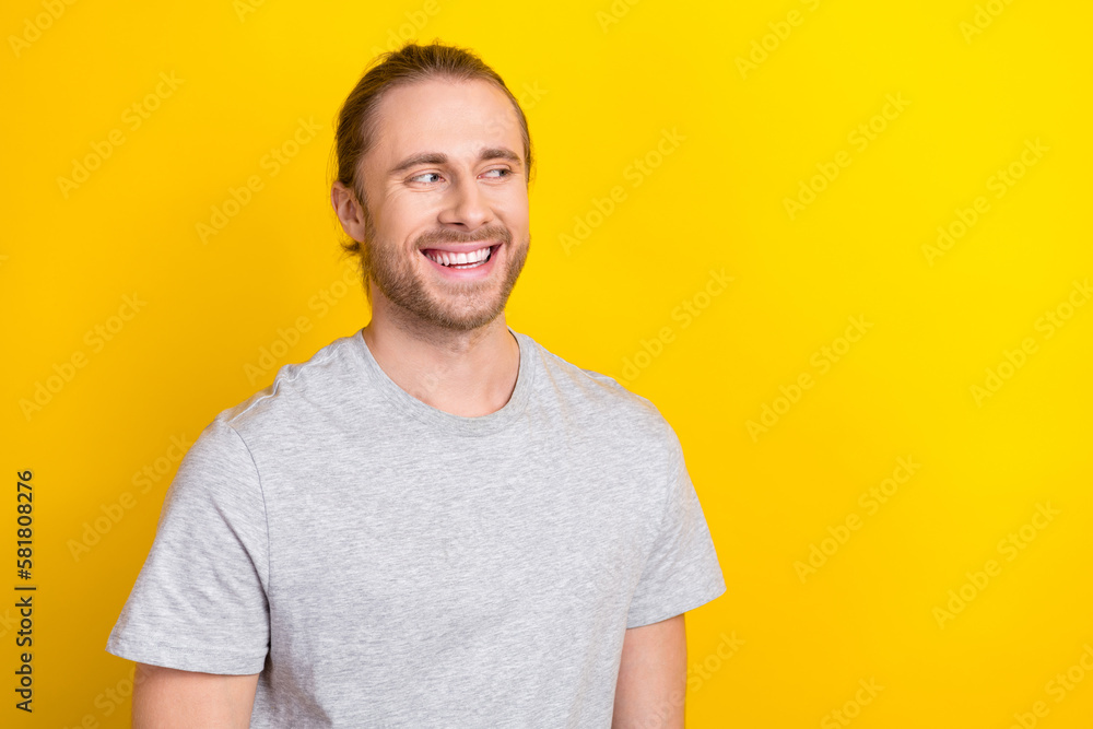 Portrait of good mood satisfied guy with long tail hair dressed light t-shirt look empty space isolated on yellow color background Portrait of good mood satisfied guy with long tail hair dressed light t-shirt look empty space isolated on yellow color background