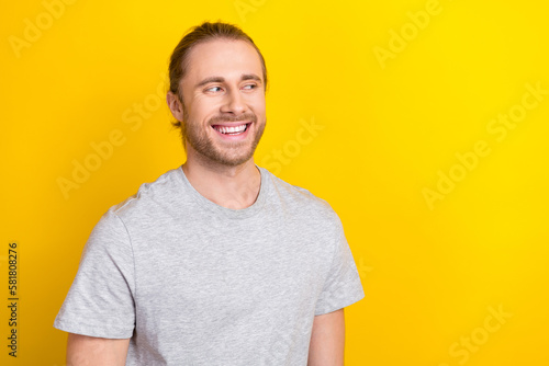 Portrait of good mood satisfied guy with long tail hair dressed light t-shirt look empty space isolated on yellow color background