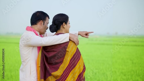 Rear view shot of village farmer showing paddy famland to wife - concept of rural family relationship, harvesting season and crop cultivation, photo