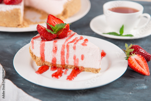 Sweet breakfast  tea and delicious cheesecake with fresh strawberries and mint  homemade recipe without baking  on dark blue stone table. Copy space.