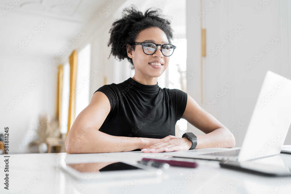 Freelancer student of the online project website. A young woman with glasses working at a workplace in an office, using a computer and tablet, coworking space. Freelancer student of the online project website. A young woman with glasses working at a workplace in an office, using a computer and tablet, coworking space.