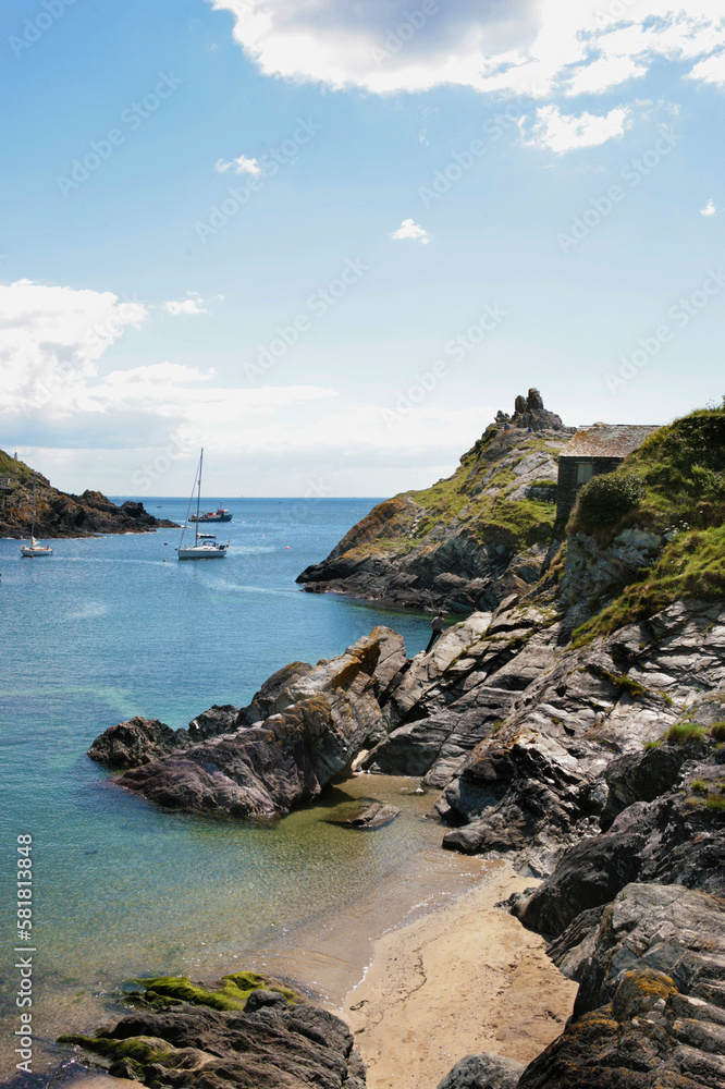 The narrow entrance to the little fishing port of Polperro, Cornwall, UK, with Peak Rock on the right