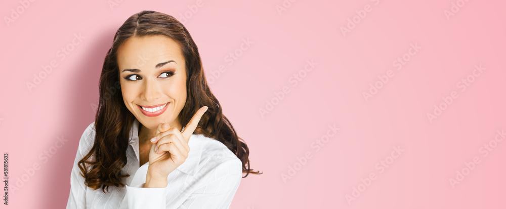 Young happy smiling woman in confident blouse, showing pointing finger aside at copy space. Business ad concept. Brunette businesswoman, isolated on rose pink background. Wide image. Young happy smiling woman in confident blouse, showing pointing finger aside at copy space. Business ad concept. Brunette businesswoman, isolated on rose pink background. Wide image.