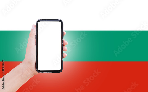 Male hand holding smartphone with blank on screen, on background of blurred flag of Bulgaria. Close-up view.