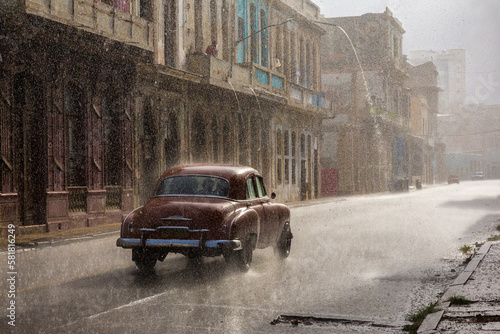 Vintage car driving through the rain in Havana. © Dan