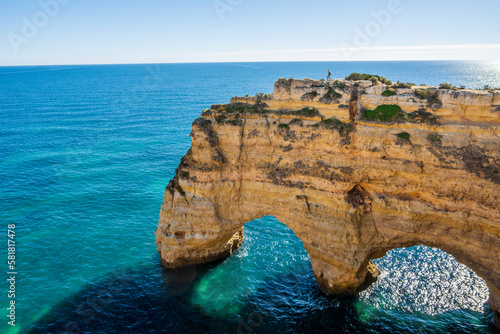 A woman on the top of cliffs at Marinha Beach in Algarve, Portugal photo