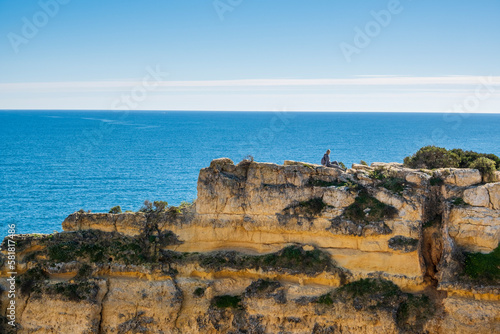 A woman on the top of cliffs at Marinha Beach in Algarve, Portugal