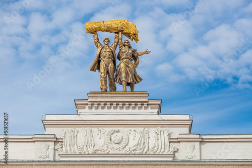 Close-up. Sculpture against the blue sky on the roof of the arch of the main entrance of the VDNH "Tractor driver and collective farmer" after restoration. Russia, Moscow, VDNH.