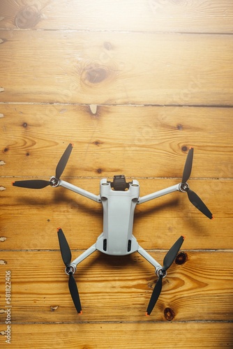 Vertical shot of a small size drone placed on a wooden background photo