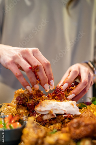 hungry woman hand holding and eatting fried chicken meat in pub