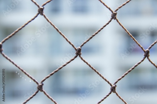 Closeup shot of a chain link fence with a blurry white background
