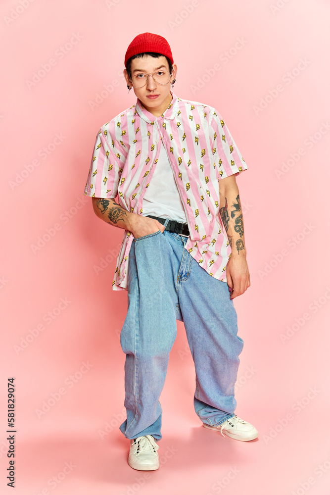 Portrait of stylish guy with tattoo keeping hand in pocket and looking at camera over pink background. Portrait of stylish guy with tattoo keeping hand in pocket and looking at camera over pink background.