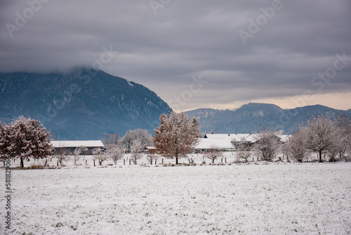 Beautiful view of a snow-covered field with houses and mountains in the background