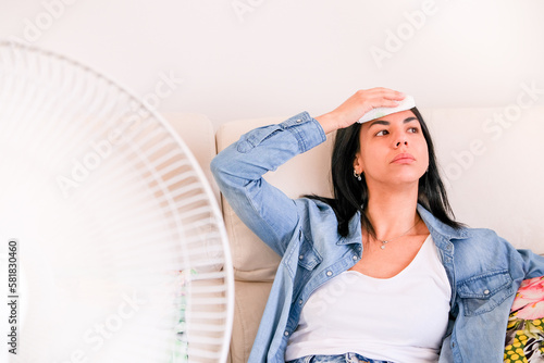 One woman sitting in her home, suffering from a heat wave seeking relief from the hot and humid temperatures