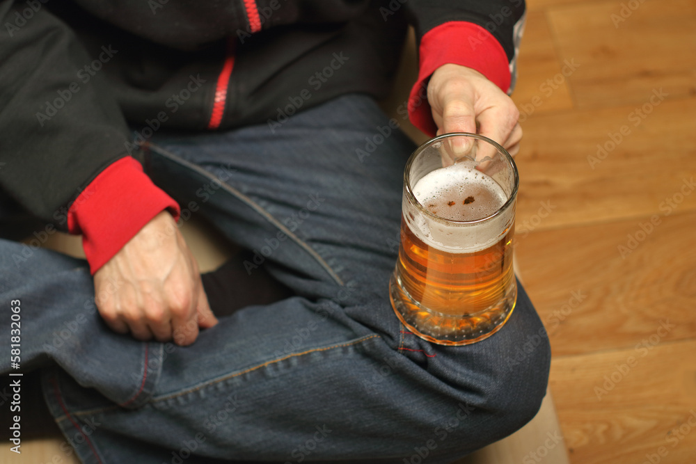 a young man holds a full mug of beer in his hand