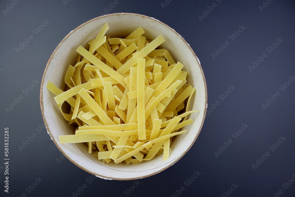 Egg noodles in a round paper package on a gray background. View from above. Egg noodles in a round paper package on a gray background. View from above.