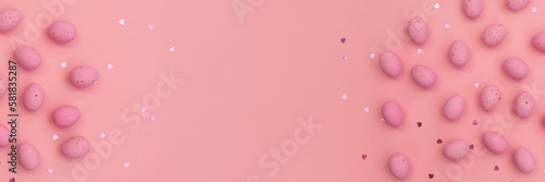 Banner made from Easter pink chocolate eggs on pastel pink background. Shimmering glowing hearts. Minimalist composition. Use in marketing materials, decorative element in variety of contexts