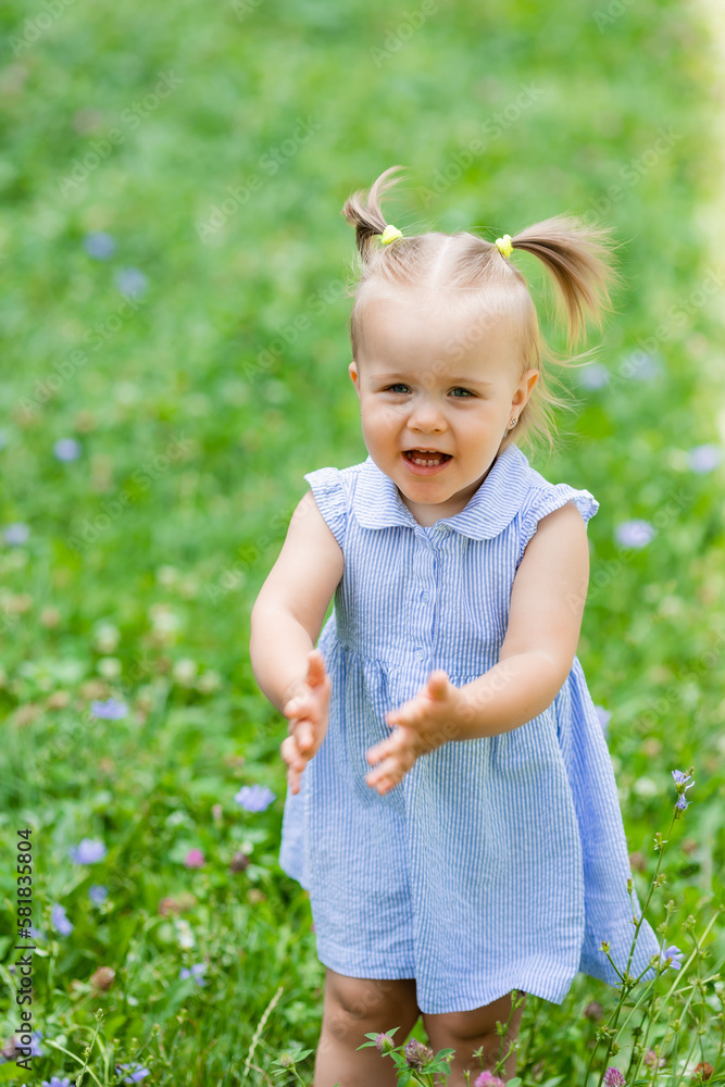 a happy little blonde girl runs in the park in the summer on the green grass. Earth Day. Children Protection Day a happy little blonde girl runs in the park in the summer on the green grass. Earth Day. Children Protection Day