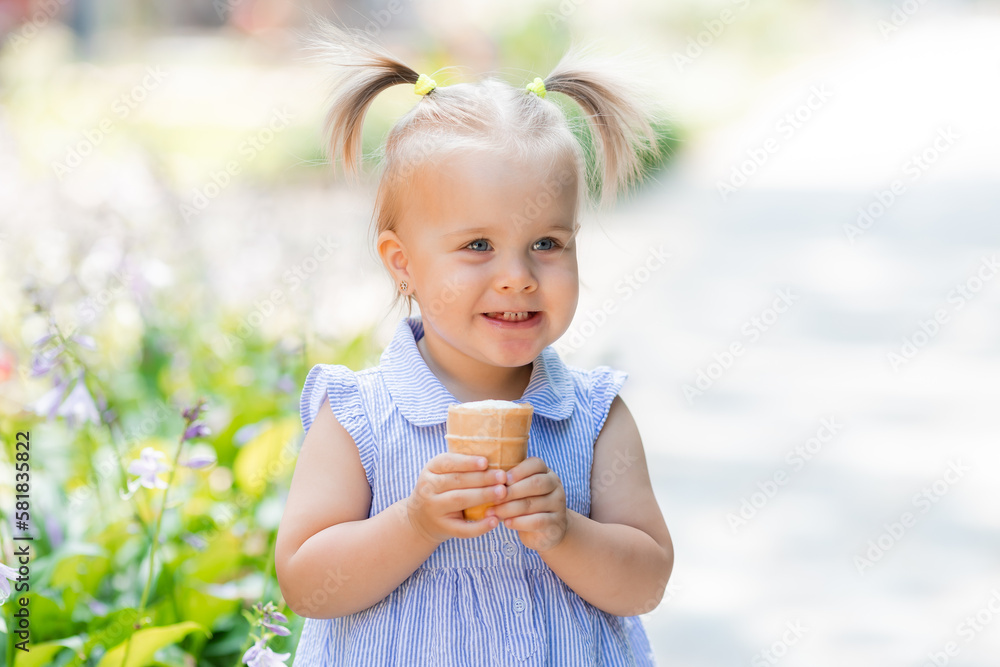 a happy little blonde girl eats ice cream in the park in the summer. Earth Day. Children Protection Day a happy little blonde girl eats ice cream in the park in the summer. Earth Day. Children Protection Day
