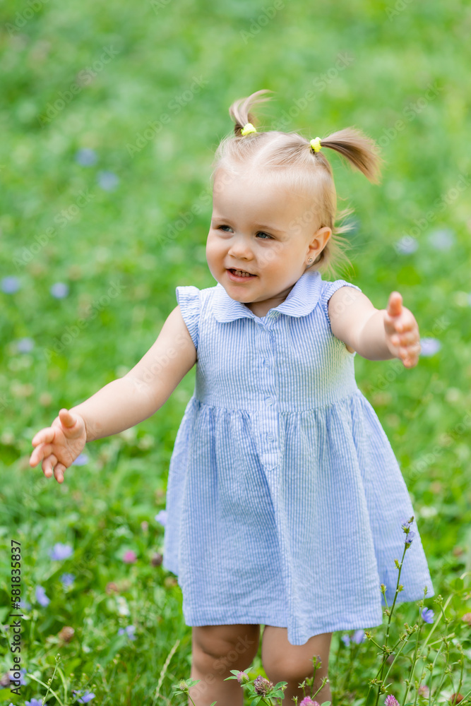 a happy little blonde girl runs in the park in the summer on the green grass. Earth Day. Children Protection Day a happy little blonde girl runs in the park in the summer on the green grass. Earth Day. Children Protection Day