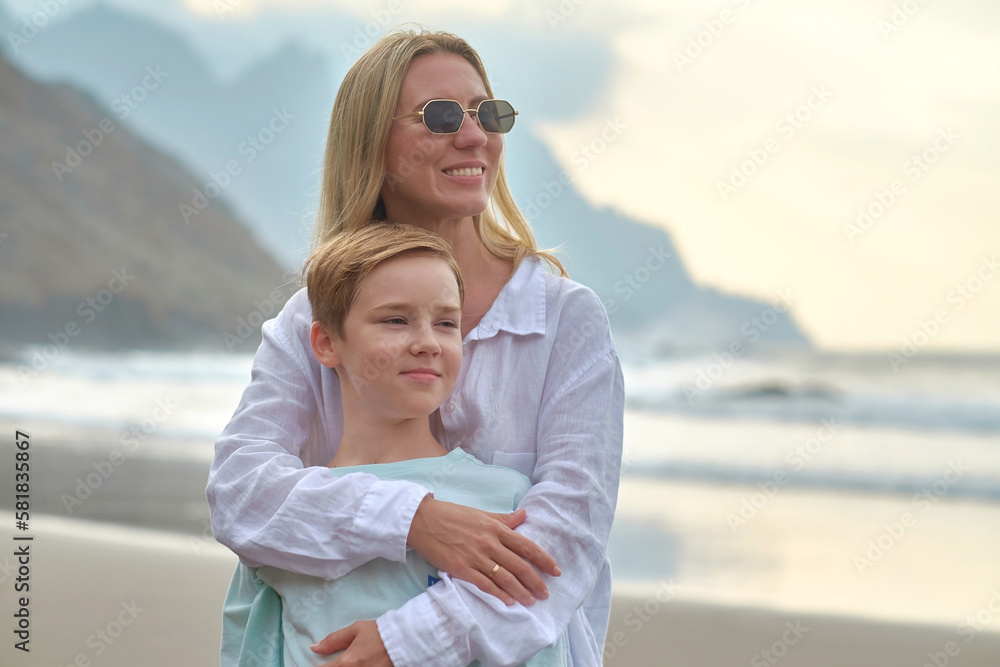 Happy family, mother and son enjoying, relaxing, playing, laughing on the beach. Mother hugging child, Mothers Day