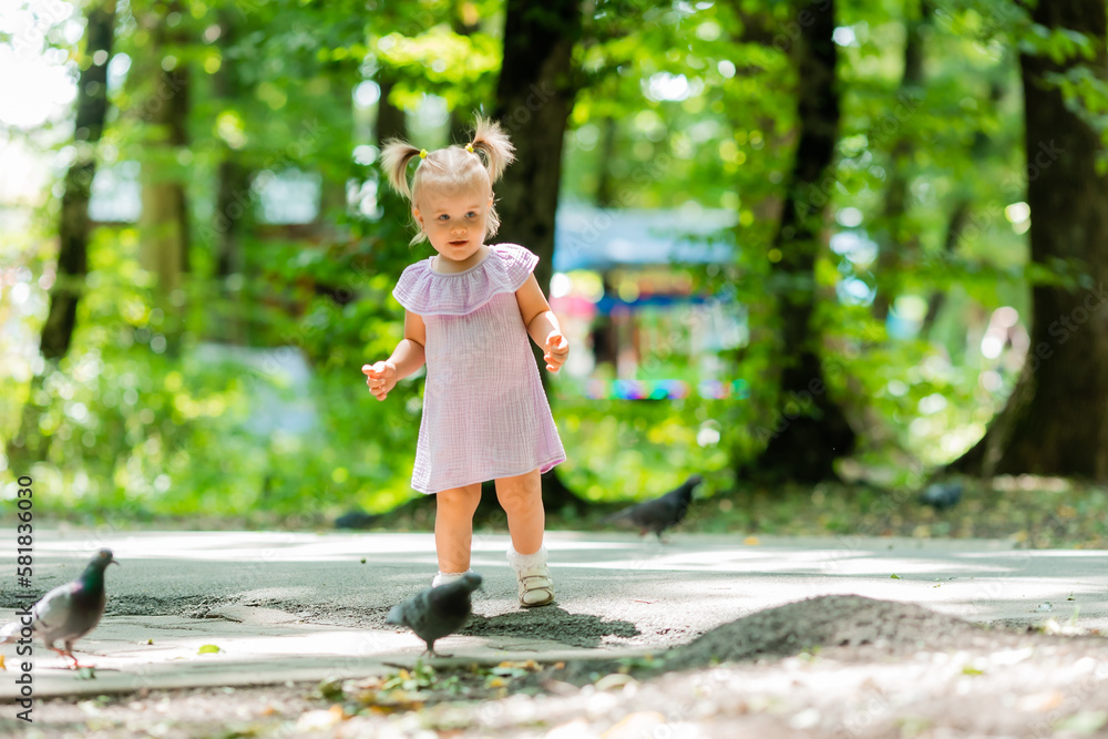 cute little girl in a purple muslin dress walks in the park in the woods in summer.Earth Day. Children Protection Day cute little girl in a purple muslin dress walks in the park in the woods in summer.Earth Day. Children Protection Day