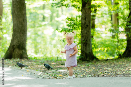 cute little girl in a purple muslin dress walks in the park in the woods in summer.Earth Day. Children Protection Day