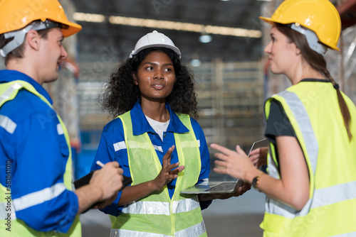 Male and female warehouse workers working and standing talking together at the storage warehouse. Group of warehouse workers discuss and training work in distribution branch