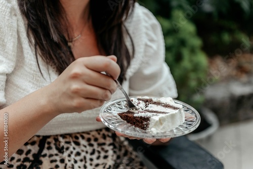 Closeup shot of a female sitting and eating a slice of cake photo