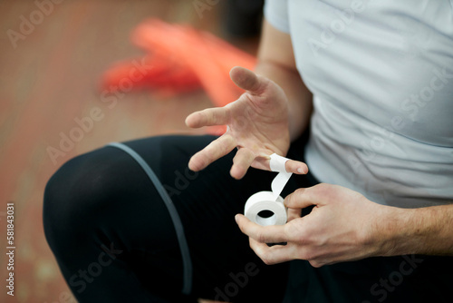 Tableau sur toile Volleyball player wrapping his fingers in protective plasters