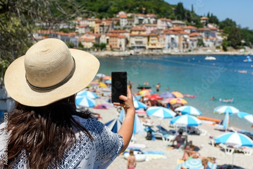 Closeup of a girl taking photos of the crowded beach in Moscenicka Draga in Croatia photo