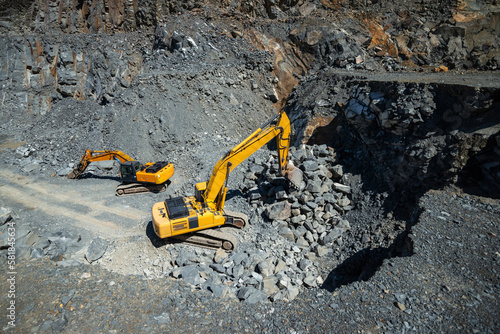 Excavator and hydraulic hammer in a diorite stone quarry