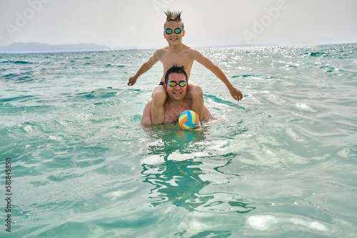 Happy family outdoors summer, father and son bonding, play ball, swim in the sea looking at view enjoying summer vacation. Togetherness Friendly concept  © Andrii IURLOV