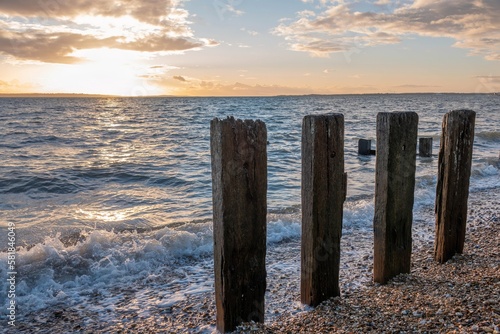 waves and groynes on beautiful deserted beach with orange sunset in the background