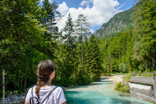 Фотография Woman standing by an azure river flowing between spruces in Triglav national par