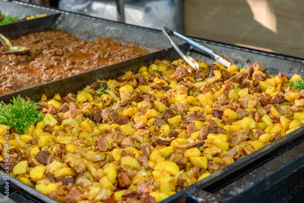 Chicken and potatoes in a large tray on a street food stall in Budapest, Hungary.