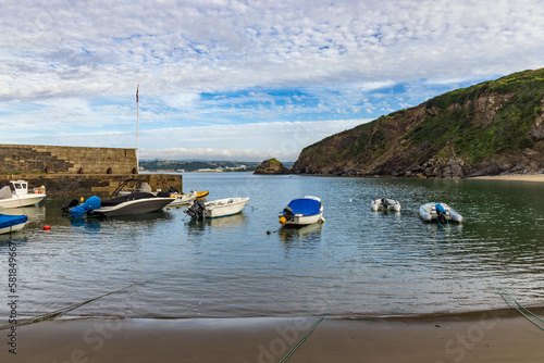 Pleasure boats berthed at Polkerris in Cornwall, a delightful sandy cove with a small harbour, on a summer morning. photo