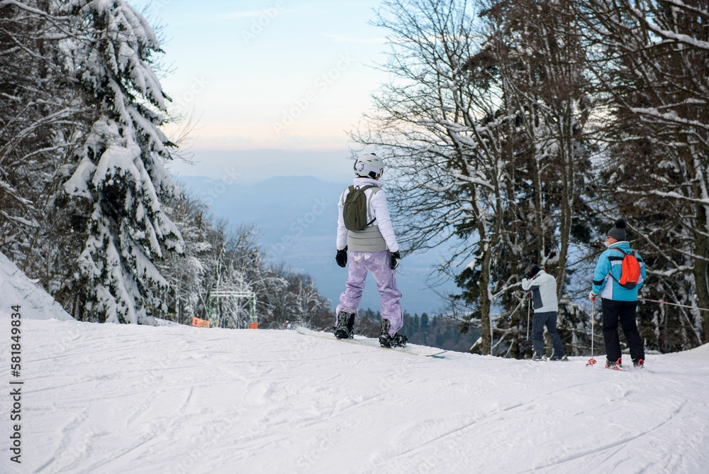 Scenic view of kids on a ski slope in a forest surrounded by snow